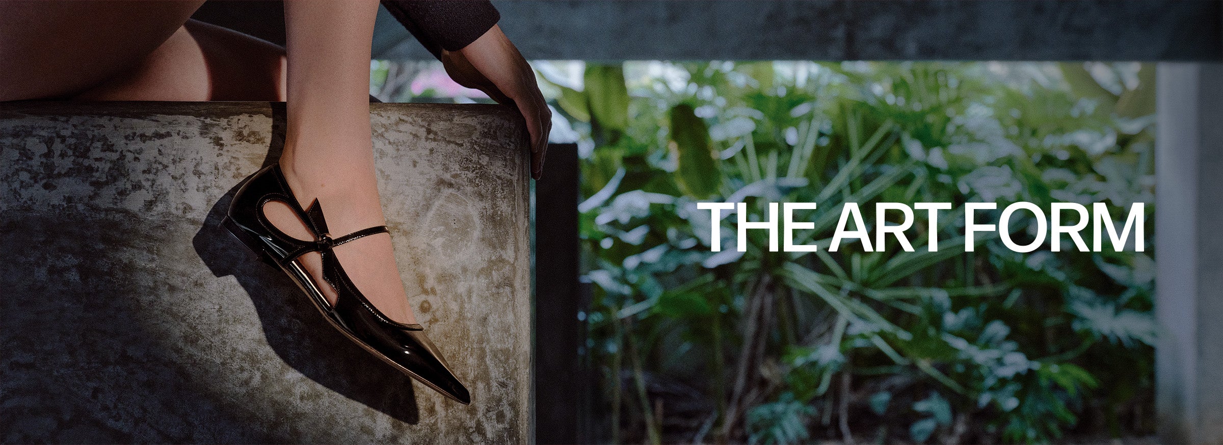  A person's foot in a black patent leather shoe with intricate cutouts, a thin strap, and a pointed toe, next to text that reads "THE ART FORM".