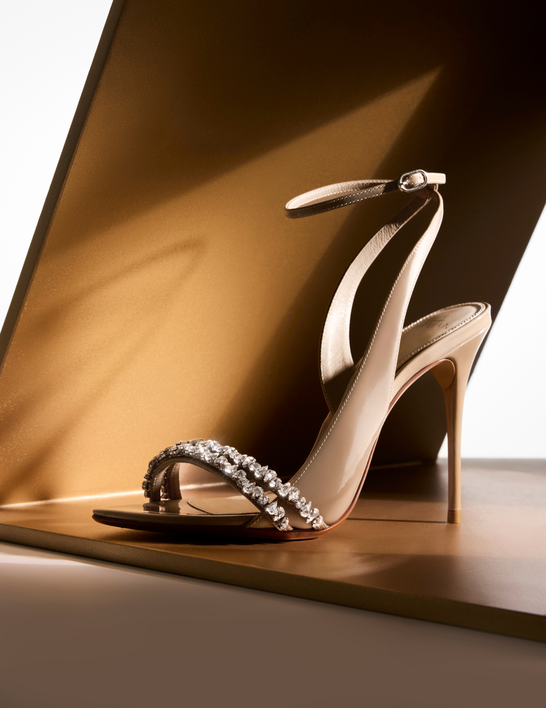 Elegant high-heeled sandal with sparkling rhinestones on the strap, set against a warm, sepia-toned background, evoking luxury and sophistication. Tap to shop.