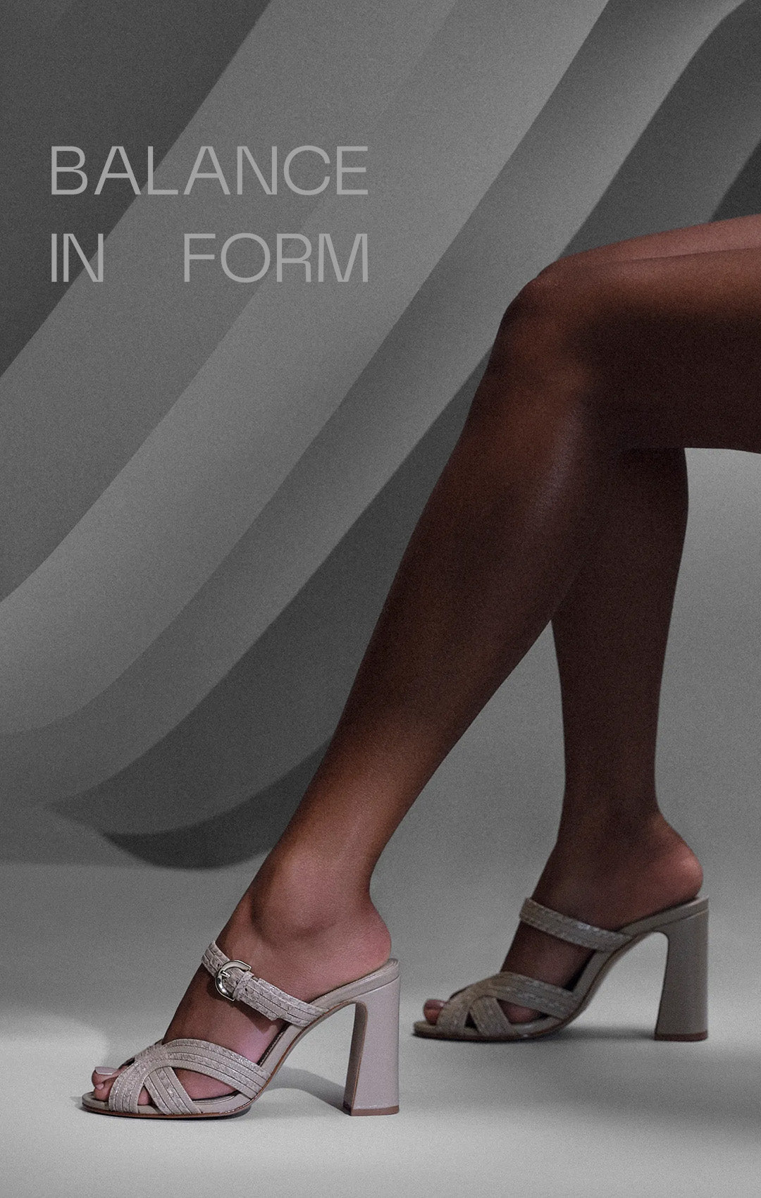  Elegant legs in beige high-heeled sandals against a minimalist gray backdrop with the text "Balance in Form" at the top, conveying sophistication. Tap to shop