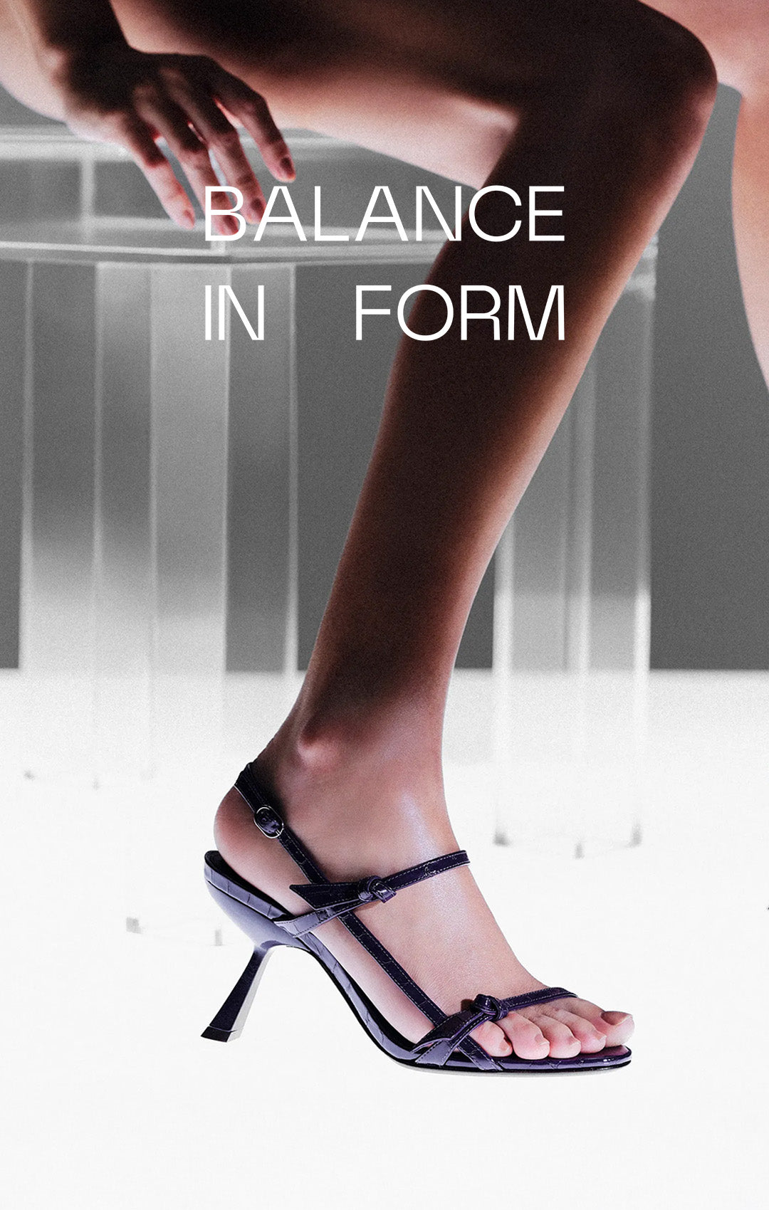  Elegant leg in a high-heeled sandal poised gracefully, with text "Balance in Form." The background features a soft grey hue, evoking sophistication. Tap to shop