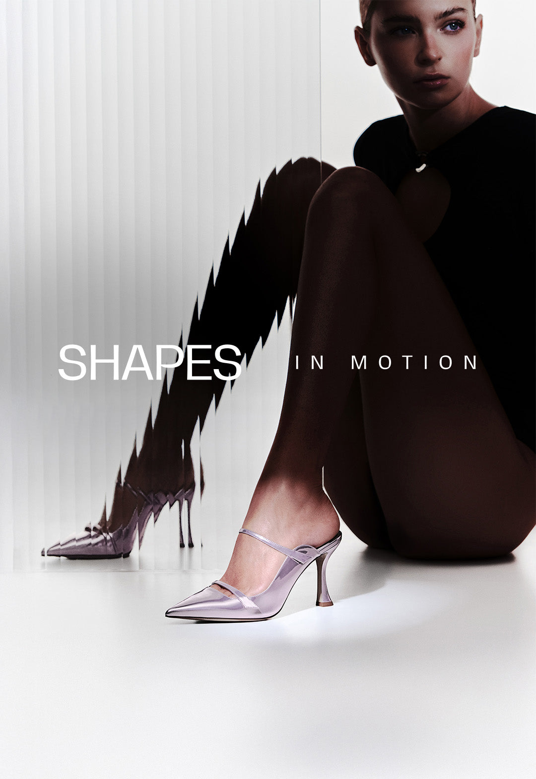  A model sitting on the floor wearing metallic lilac pointed-toe mules. A ribbed glass panel creates a visual distortion effect on the left side. Text overlay reads "SHAPES IN MOTION."