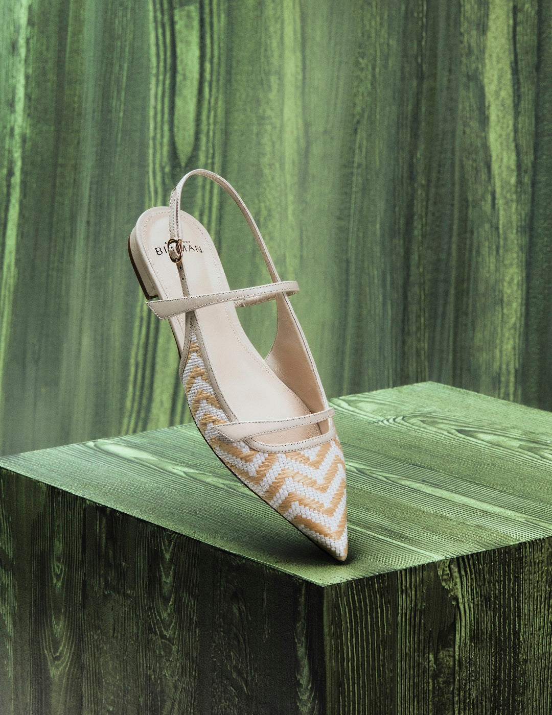 Beige slingback flat with pointed toe and raffia zigzag pattern, displayed on a green wooden platform. Tap to shop Flats